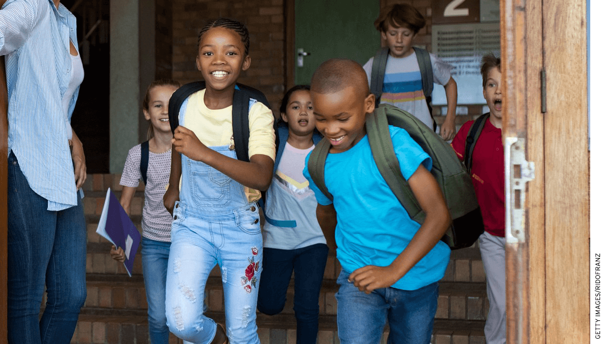 Children playfully running out of a school