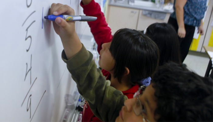 Students working on math problems on a white board