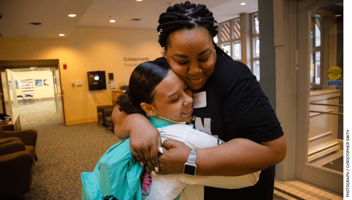 Crystalle Green, the Communities in Schools of Mid-America site coordinator for Cross- roads Preparatory Academy in Kansas City, Missouri, hugs a student headed to class during a "Motivational Monday" event.