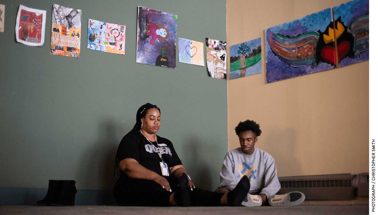 Green does a meditation exercise with student Jayshon Anderson in a room featuring student-created art.