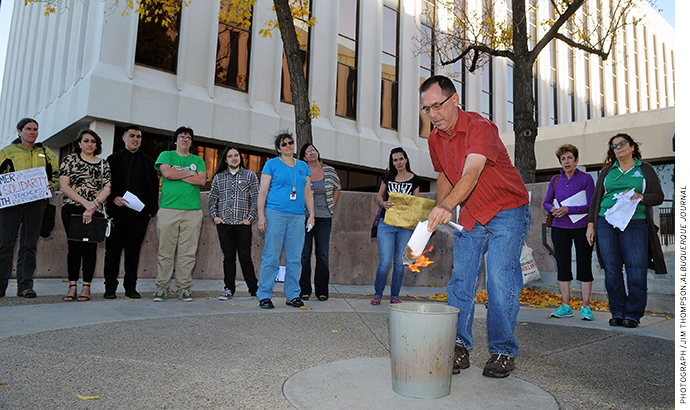 An elementary school teacher burns his evaluation during a protest in front of the Albuquerque Public Schools headquarters in October 2016.