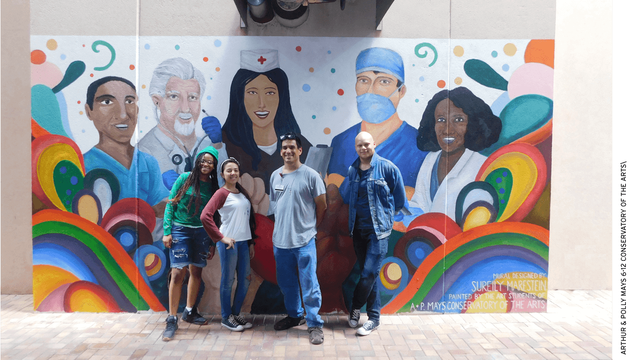 Art teacher Gerald Obregon and students from Arthur & Polly Mays Conservatory of the Arts, a public school, in front of a mural they painted on a wall at Kendall Regional Medical Center.