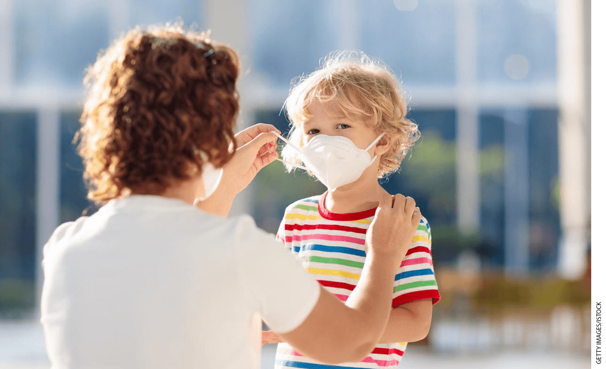 Adult fitting a surgical mask on a child