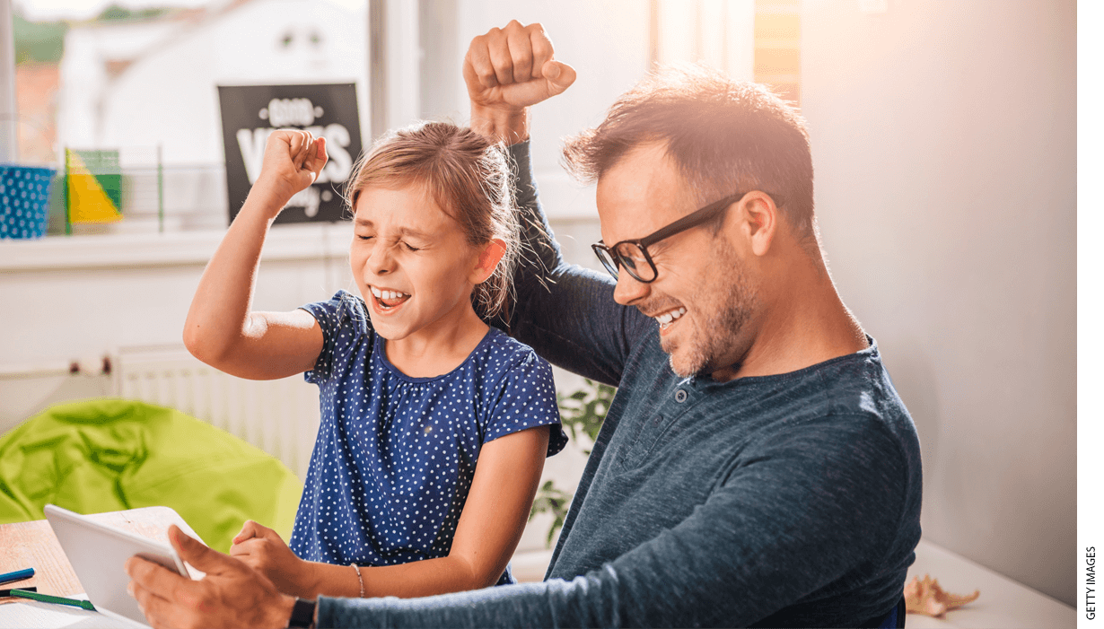 Father and daughter cheering while looking at a tablet computer