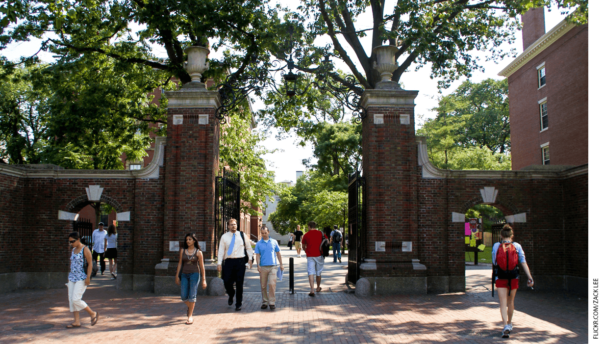 Students and faculty walking through a gate on a college campus.