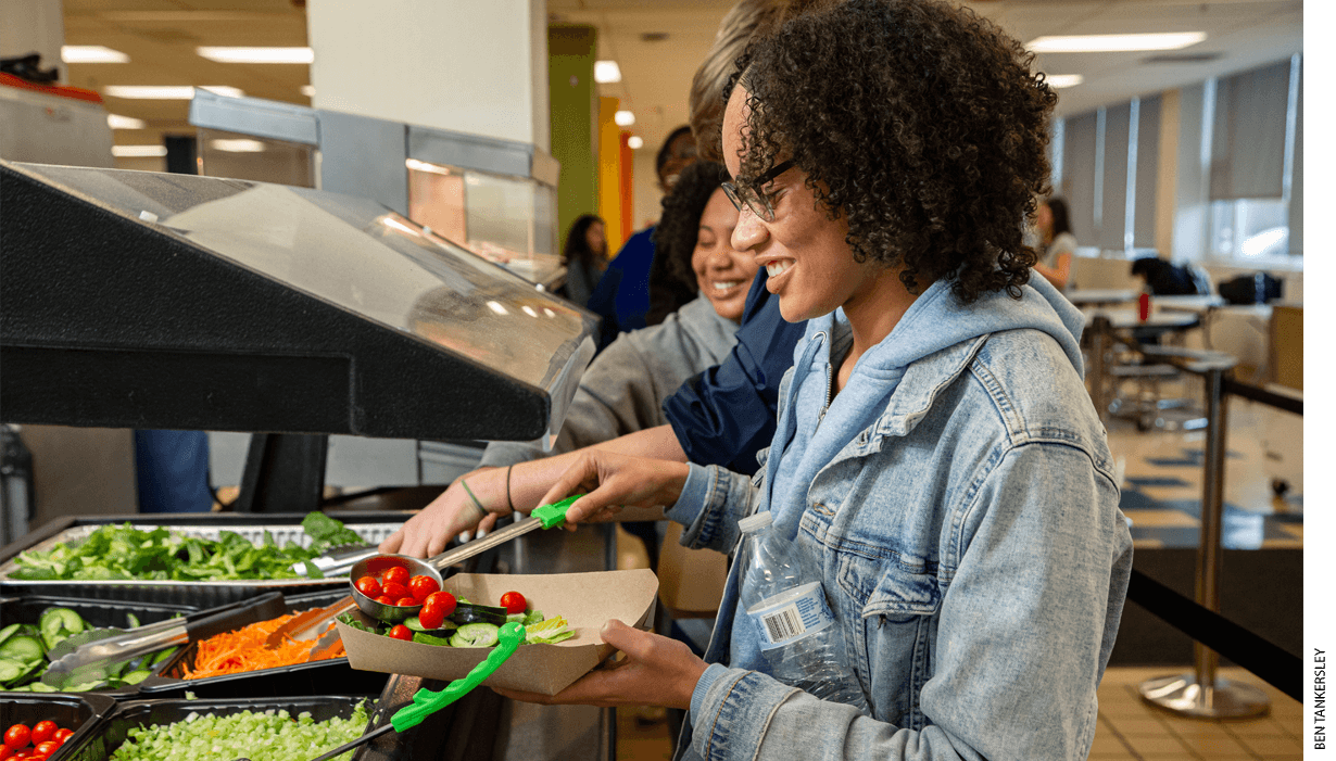 Eleventh-grade student Alanny Alvarez makes a salad at the salad bar in the cafeteria at Capital City Public Charter School in Washington, D.C.