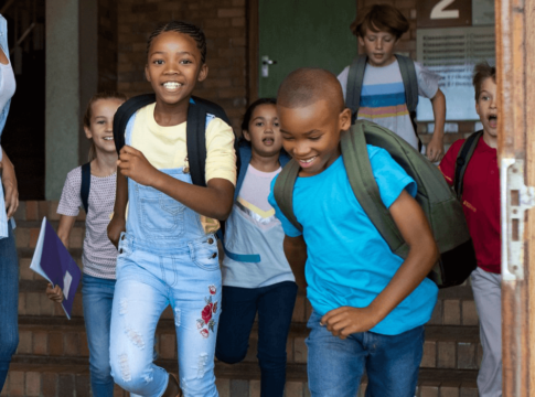 Children playfully running out of a school