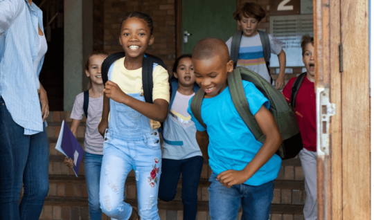 Children playfully running out of a school