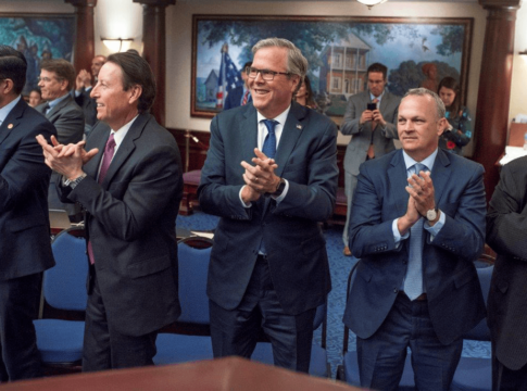 Former Florida Gov. Jeb Bush, center, applauds on the floor of the Florida House of Representatives after the passage of the Family Empowerment Scholarship program.