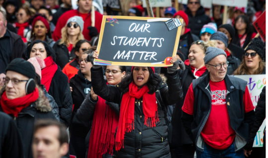 Thousands of striking Chicago Teachers Union and their supporters march around City Hall in October 2019. One person in front holds up a sign that reads, "Our Students Matter."