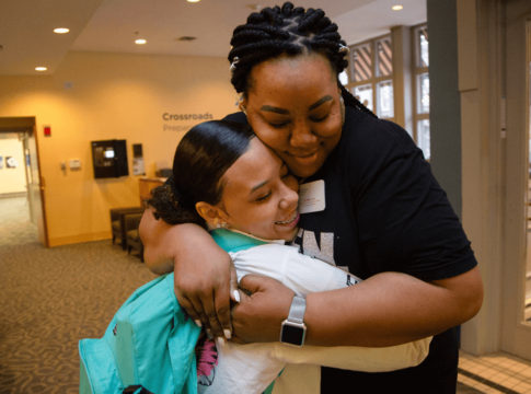 Crystalle Green, the Communities in Schools of Mid-America site coordinator for Cross- roads Preparatory Academy in Kansas City, Missouri, hugs a student headed to class during a "Motivational Monday" event.