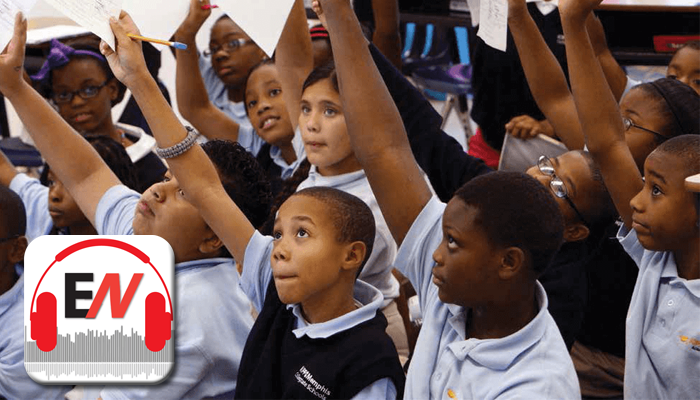 Students raising sheets of paper in the air in a classroom
