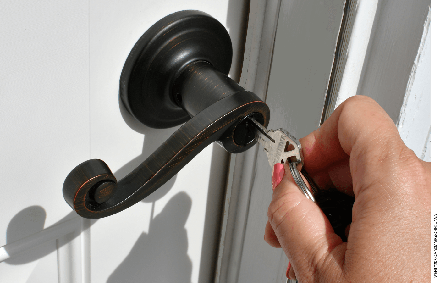 A hand inserting a key into the lock of a doornob