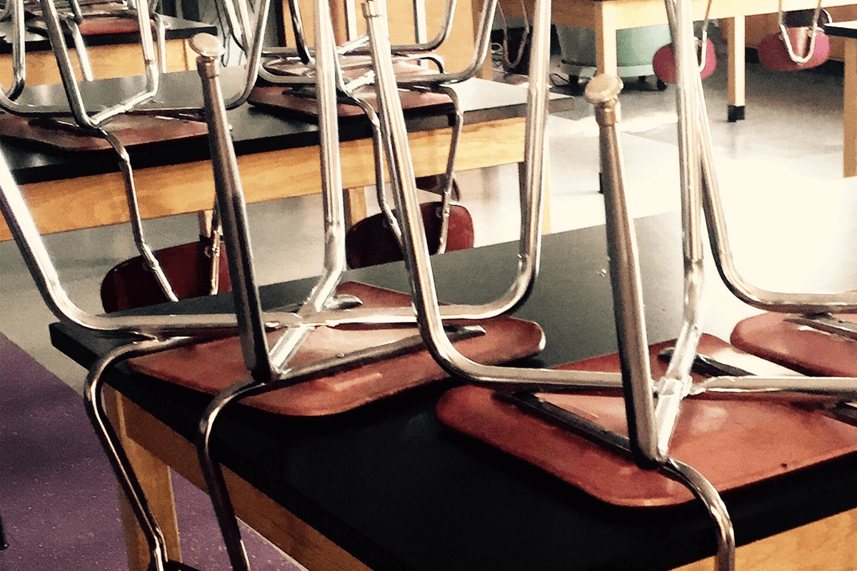 Chairs stacked on desks in a classroom