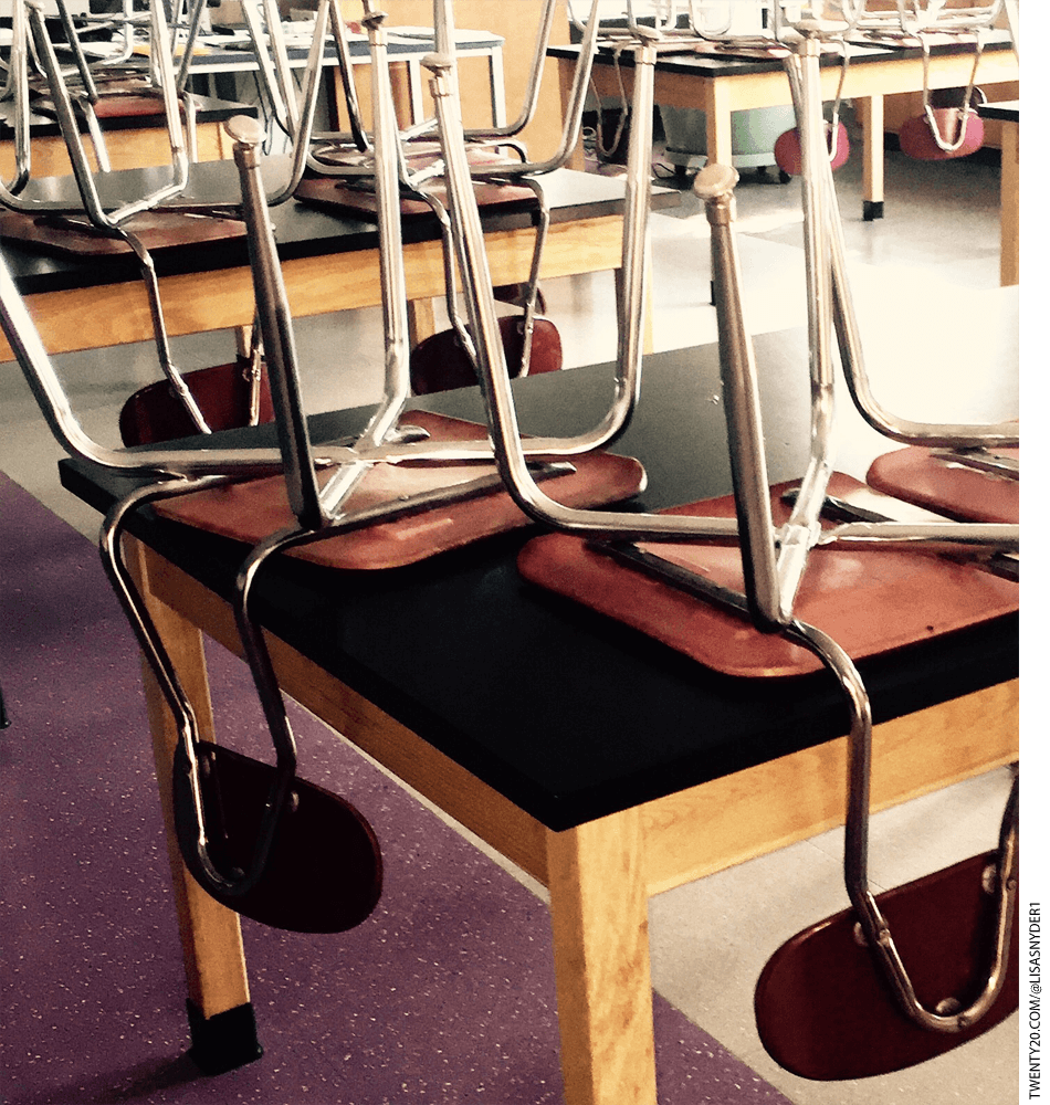 Chairs stacked on desks in a classroom