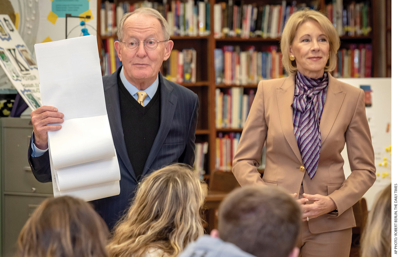 Alexander, next to Secretary DeVos, holds up the Free Application for Federal Student Aid as students at the Sevier County High School in Tennessee watch. “There are still too many questions on this form,” Alexander says.