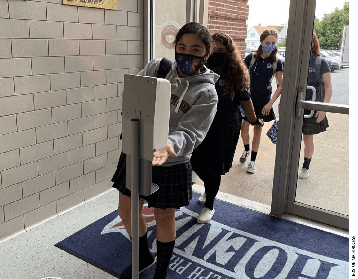 A student applies hand sanitizer at the entrance of a school