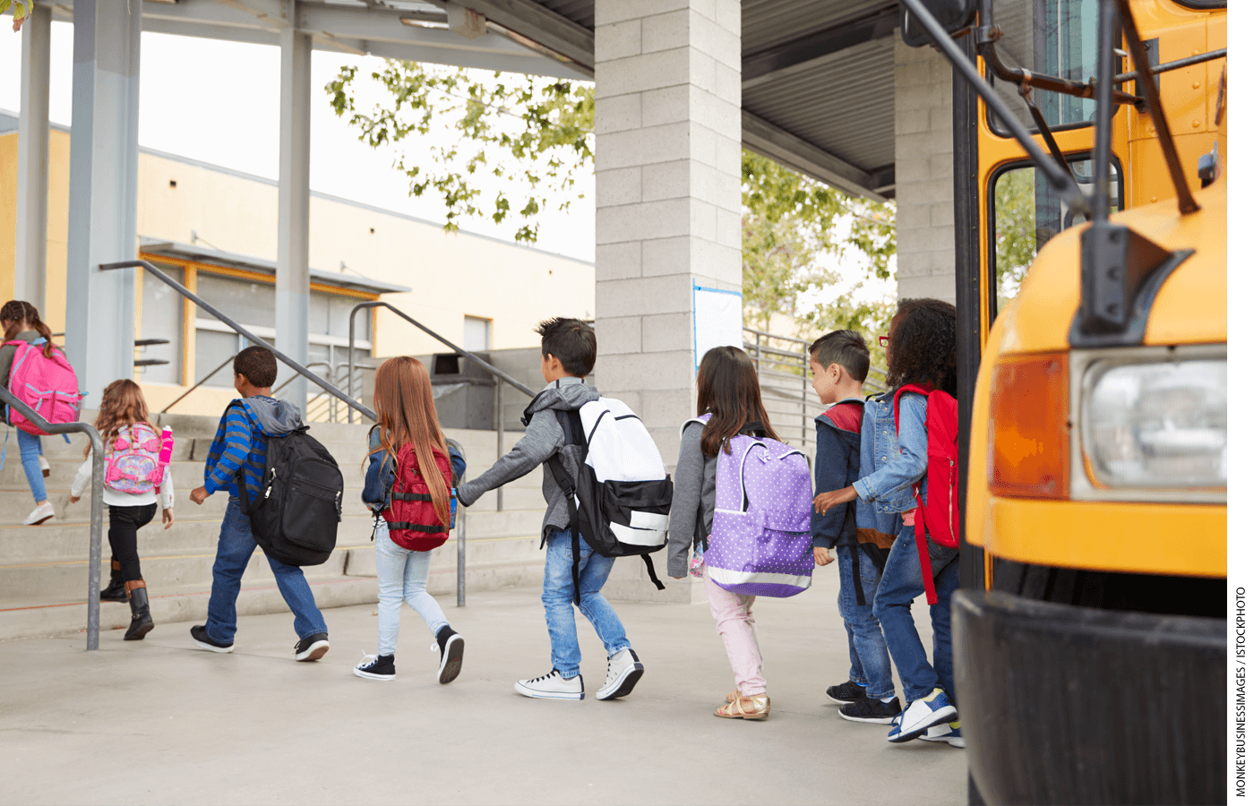 Students file off a bus and walk into a school