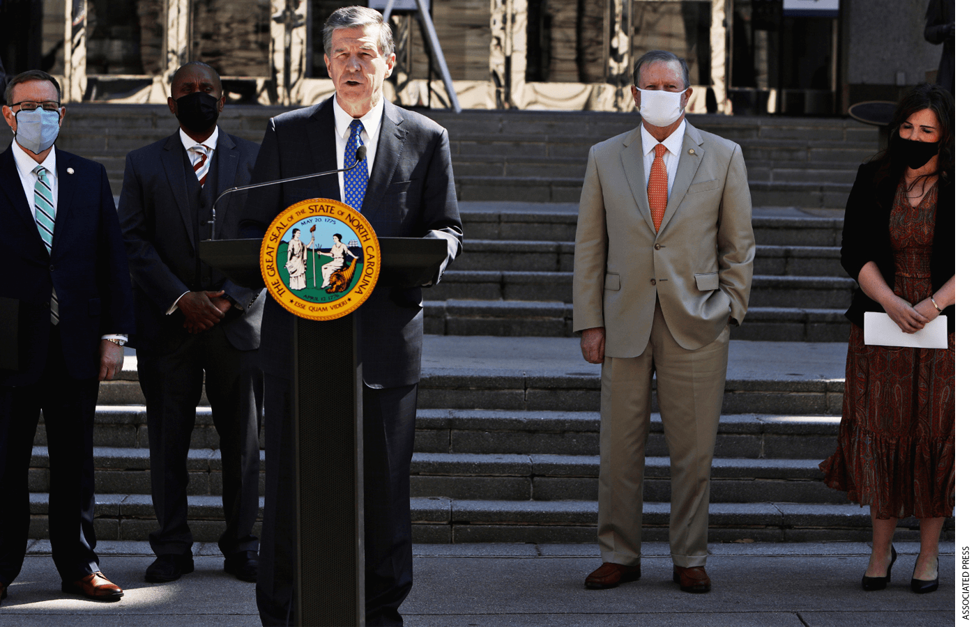 North Carolina Gov. Roy Cooper, center, and lawmakers gather Wednesday, March 10, 2021, for a news conference to announce that leaders of the state legislature and the governor have reached an agreement to reopen the state's K-12 public schools to full-time daily instruction in Raleigh.