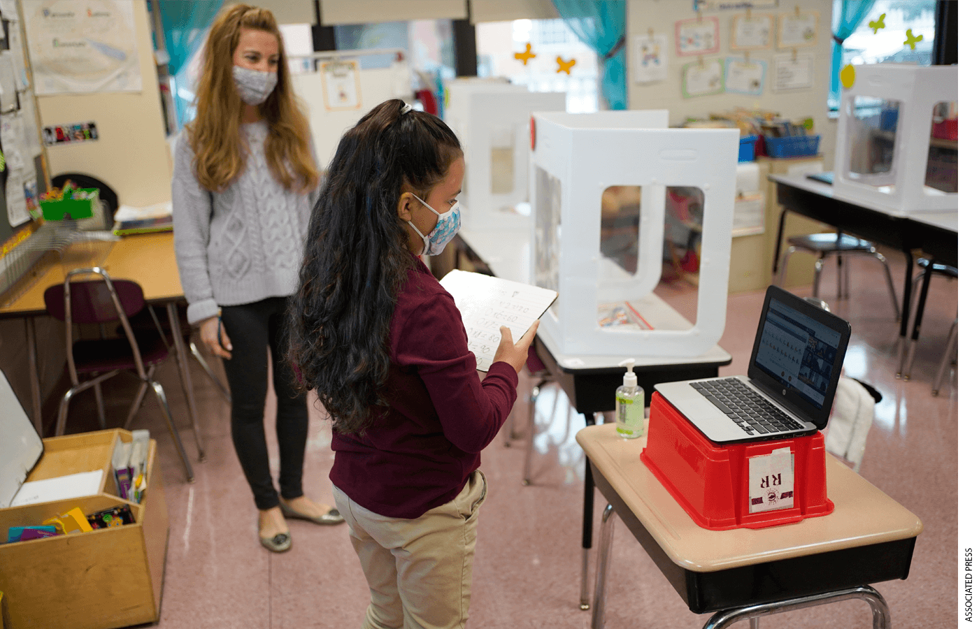 Third grader Madison Cortes, right, reads off math problems to classmates on zoom while teacher Maria Mirkovic looks on at Christa McAuliffe School in Jersey City, N.J., Thursday, April 29, 2021.