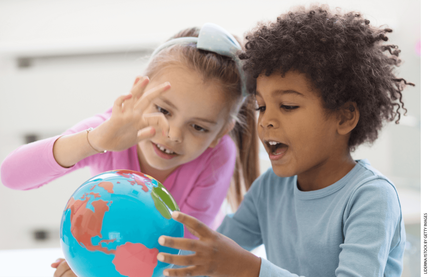 Two students in a classroom looking at a globe