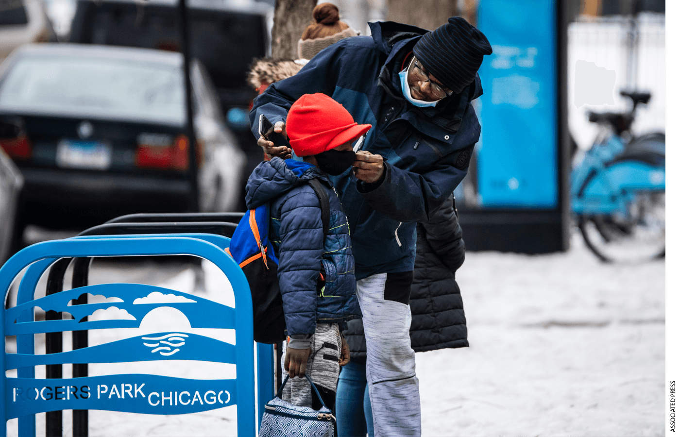 A man adjusts a boy's face mask as they arrive at Jordan Community Public School in Rogers Park on the North Side, Wednesday, Jan. 12, 2022 in Chicago. Students returned to in-person learning Wednesday after a week away while the Chicago Public Schools district and the Chicago Teachers Union negotiated stronger COVID-19 protections.