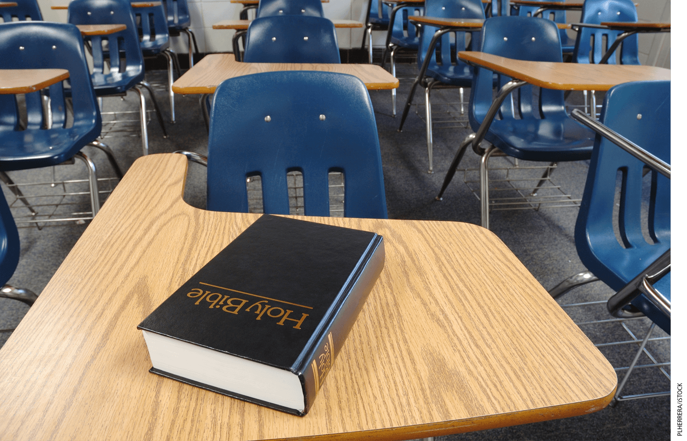 A Holy Bible sits on a school desk