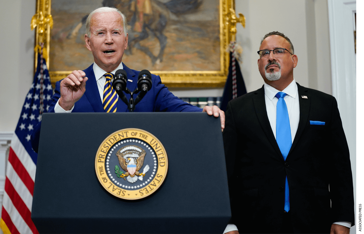 President Joe Biden speaks about student loan debt forgiveness in the Roosevelt Room of the White House, Wednesday, Aug. 24, 2022, in Washington. Education Secretary Miguel Cardona listens at right.