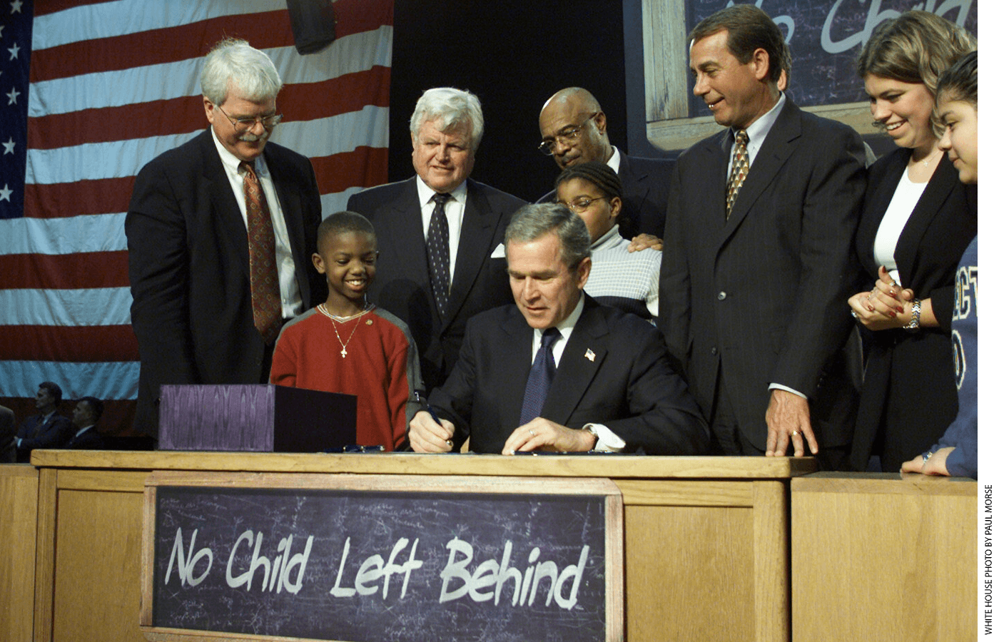 President George W. Bush signs the No Child Left Behind Act into law, with Representative George Miller and Senator Edward Kennedy behind him (from left)