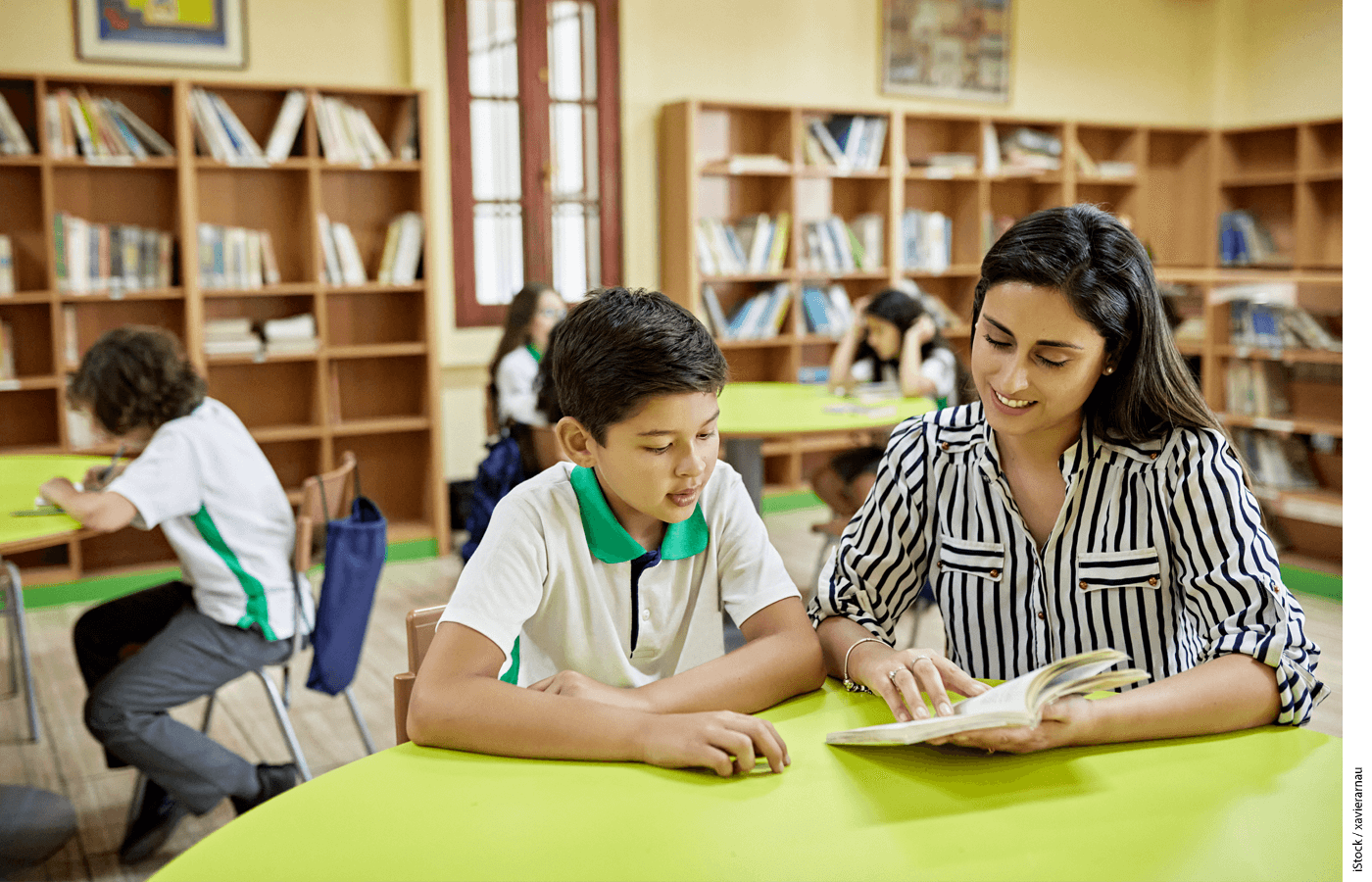 A teacher tutoring a student in reading in a classroom