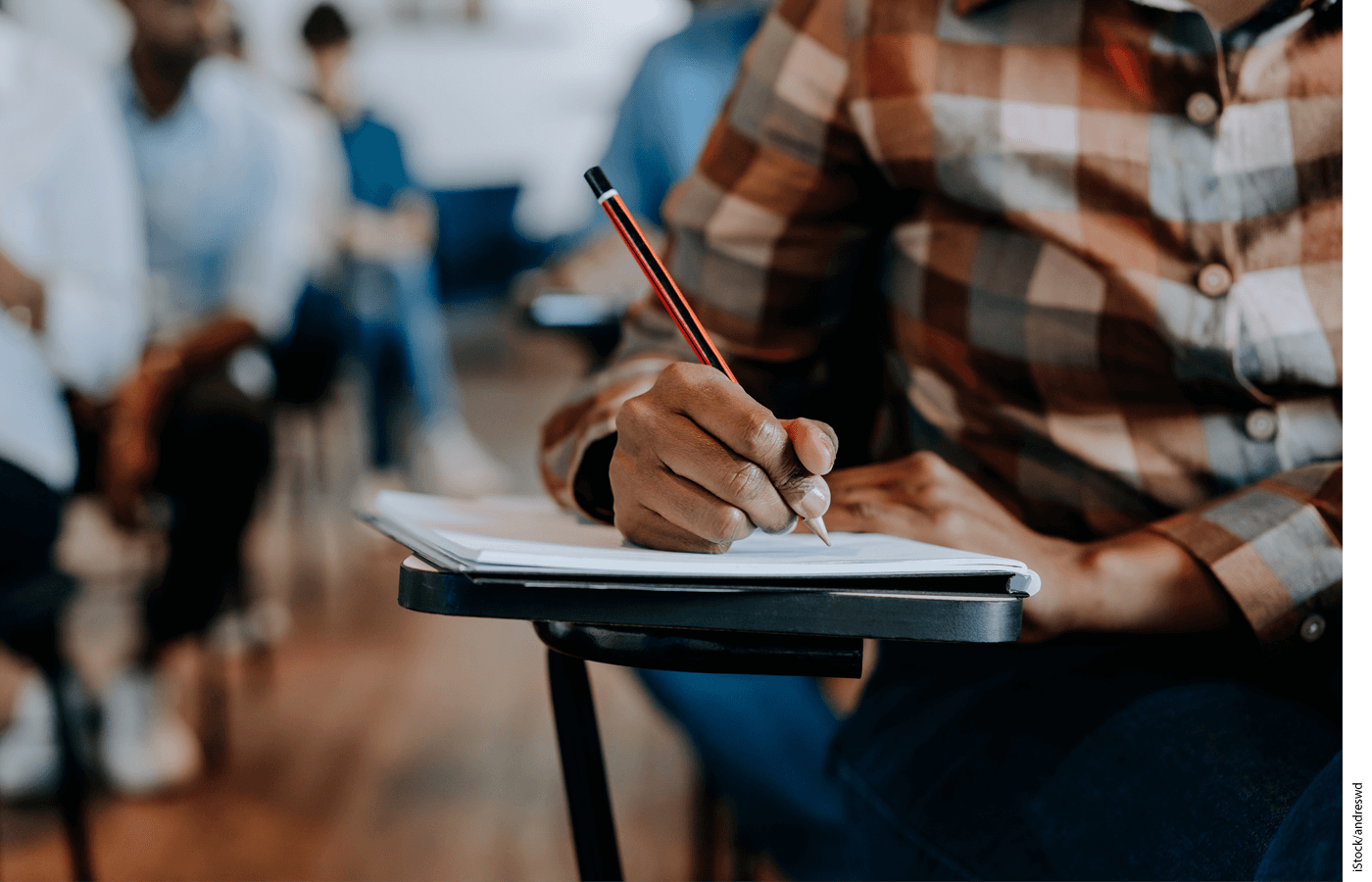 Photo of a man writing in a notebook at a desk