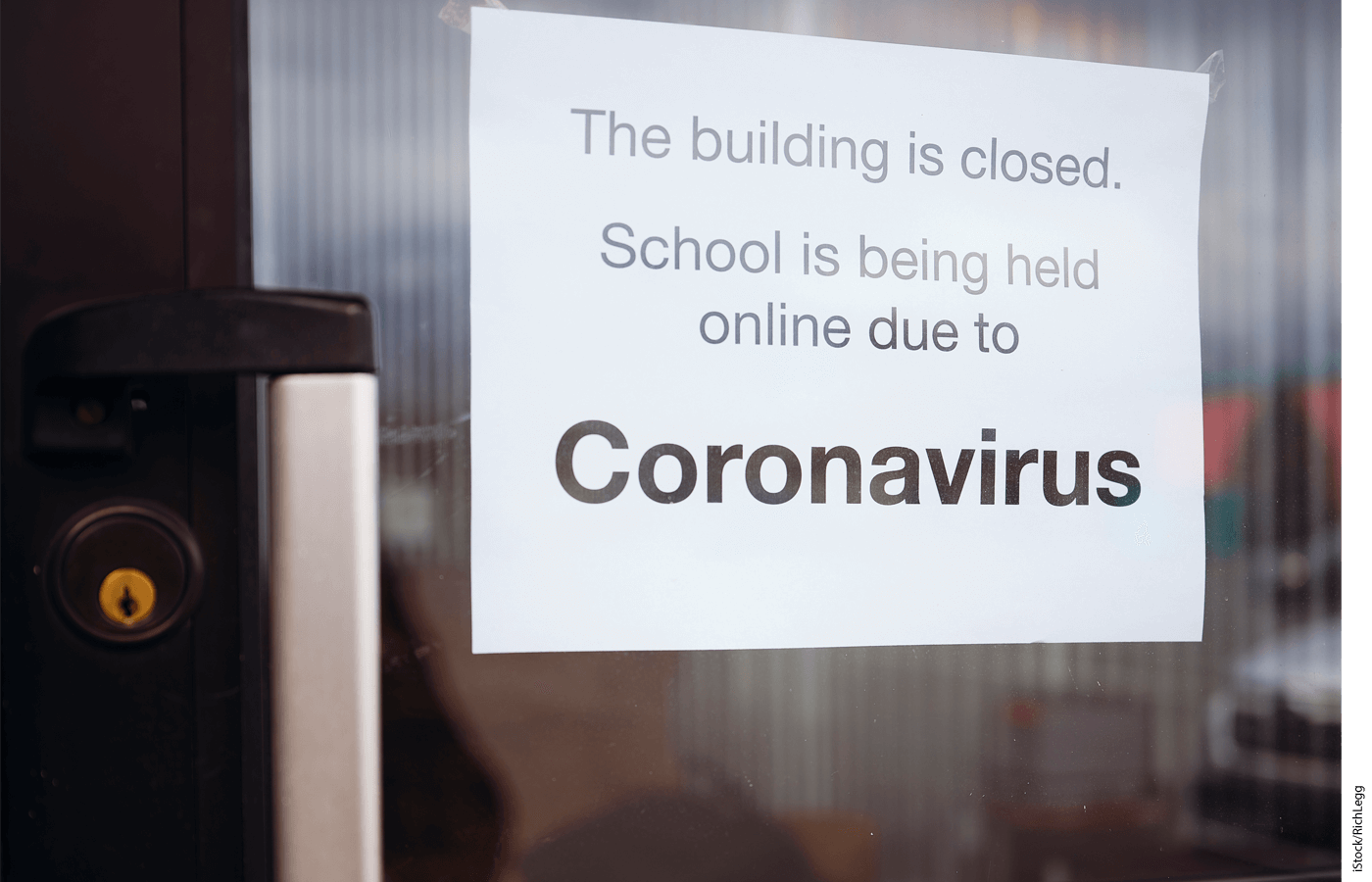 Image of a glass door with a sign that reads "The building is closed. School being held online due to Coronavirus."
