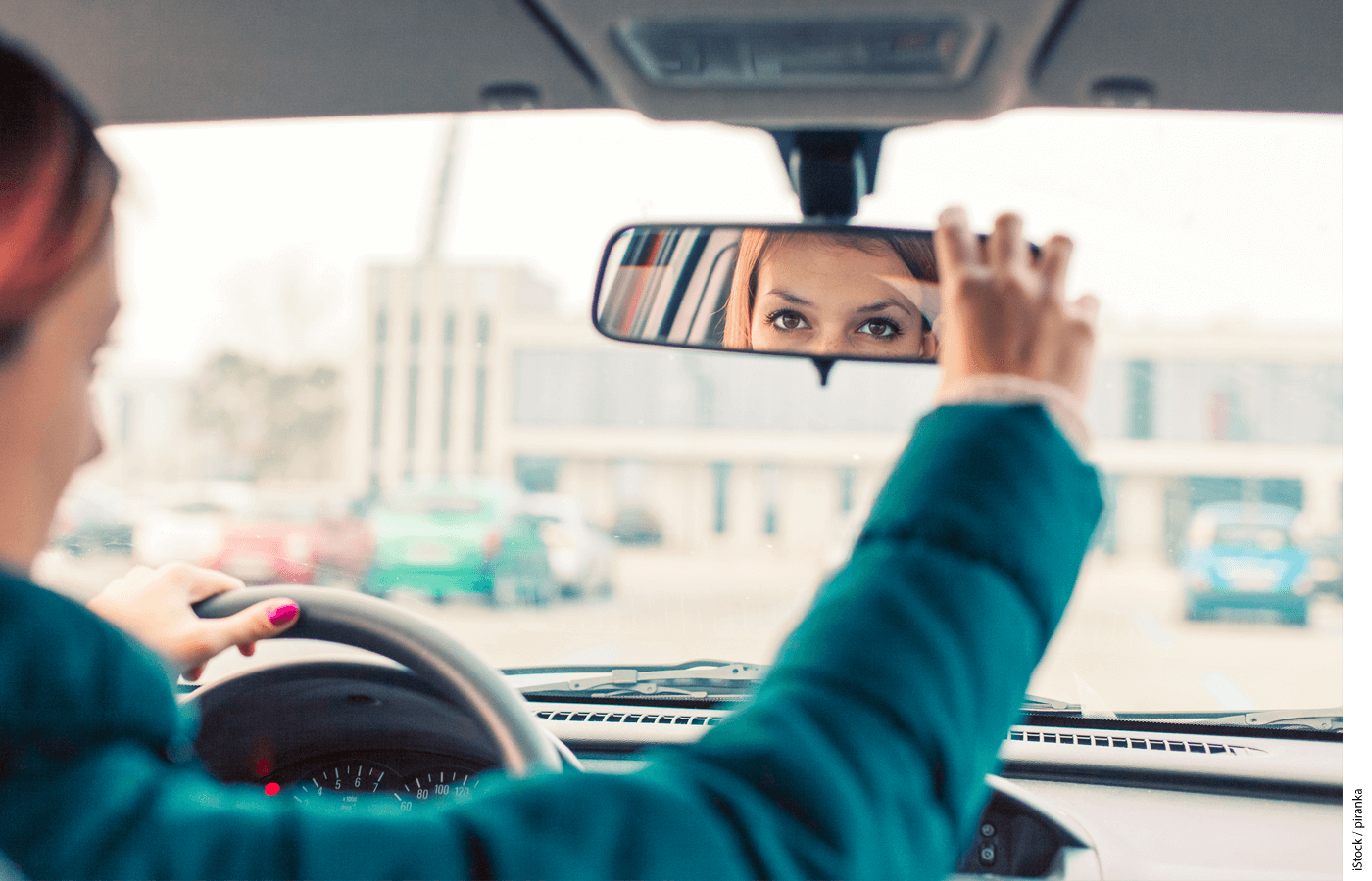 A driver adjusting her rear view mirror