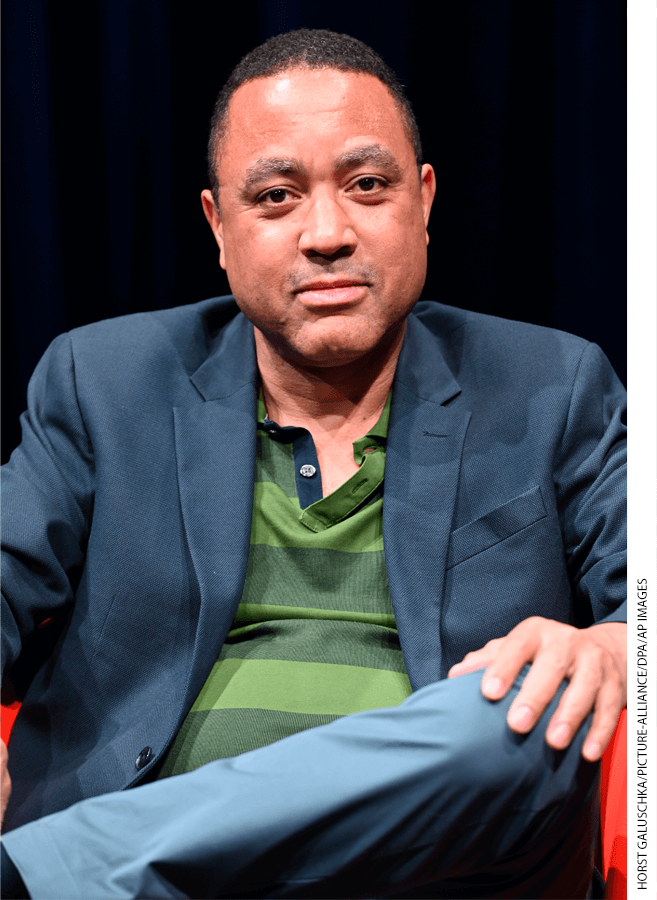 Portrait of John McWorter in dark gray blazer seated during interview