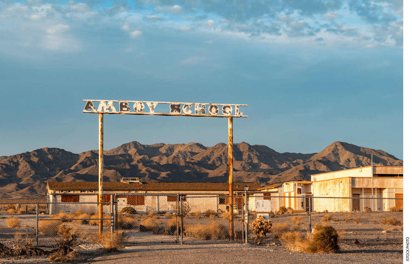 Photo of a closed school in the desert with a rusted sign that reads "AMBOY SCHOOL"