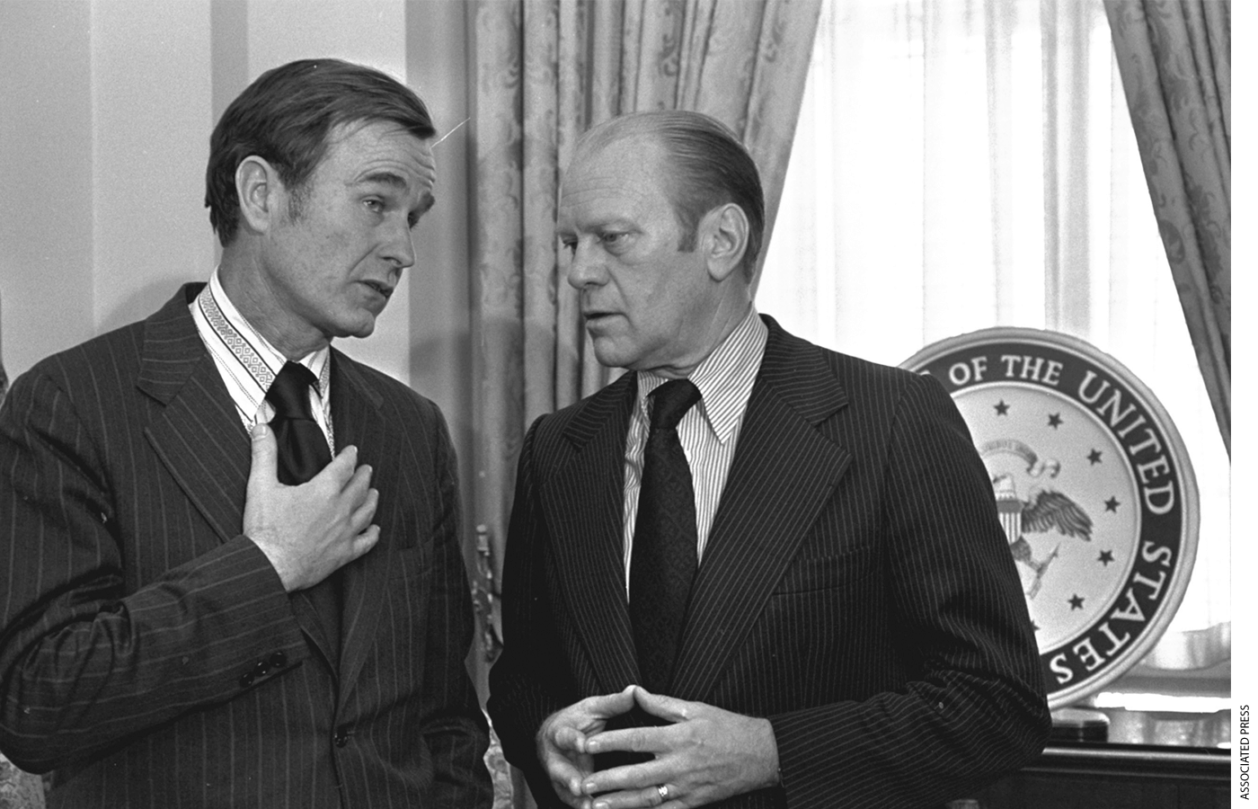 George H.W. Bush speaks with President Gerald Ford in the White House.