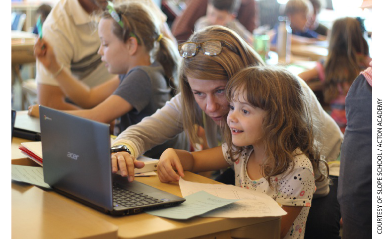 A teacher instructs a student, who is working on a laptop computer.
