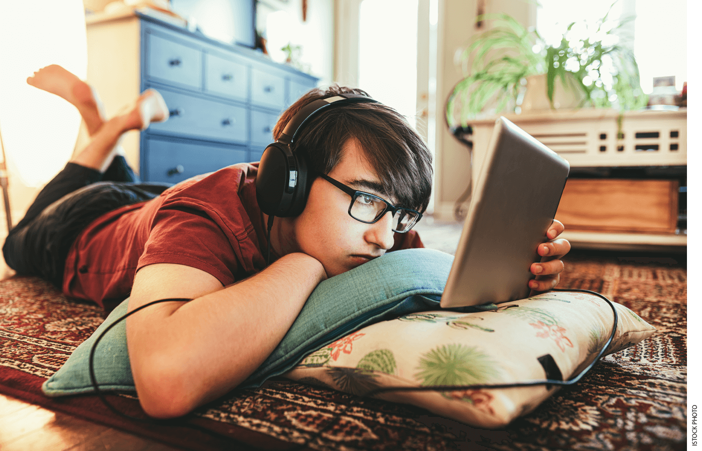 Photo of a student at home, lying on the floor reading an ipad