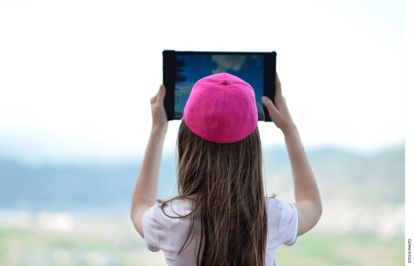 A student holds an ipad up towards the sky