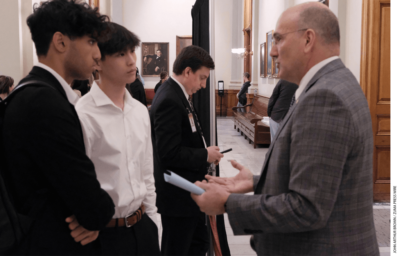 Ishan Mahajan and Justin Wang, two students from Lambert High School in Forsyth County, Georgia, discuss their opposition to the Promise Scholarship with state representative Todd Jones, a supporter, in July 2023.